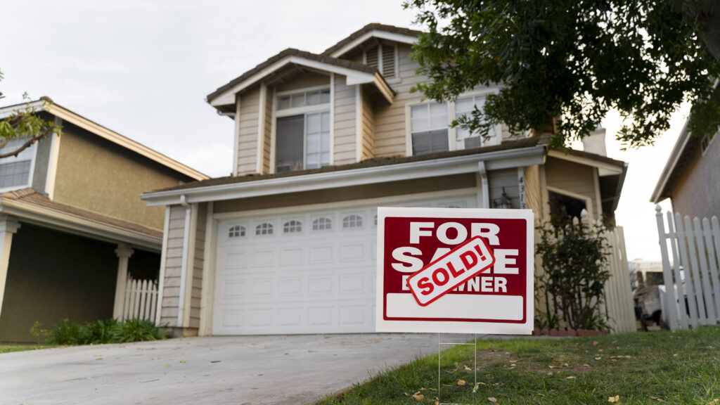 House with sold on a for sale sign in the front yard