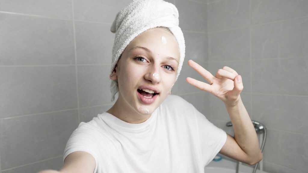 Teenage girl doing skincare and giving a peace sign