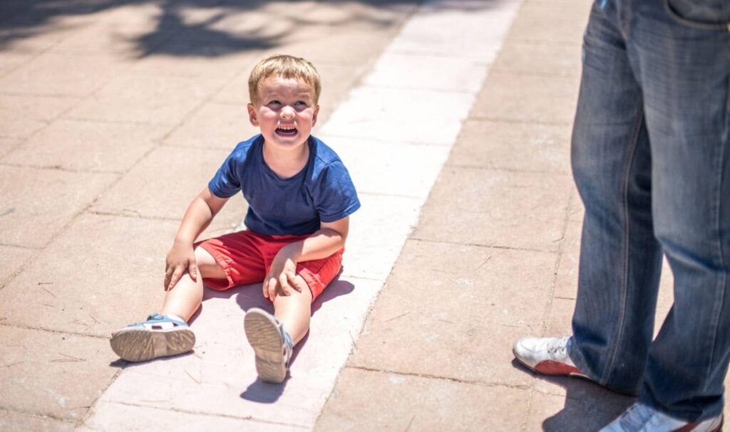 Young boy sitting on the ground crying