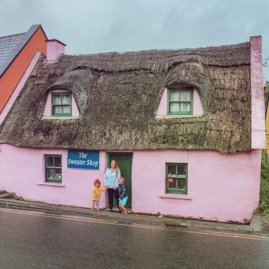Mother and sons outside a pink thatched cottage
