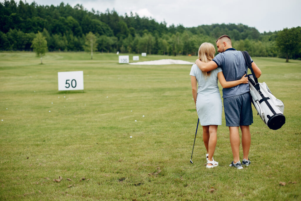 Couple with hands around each other while walking on a golf course
