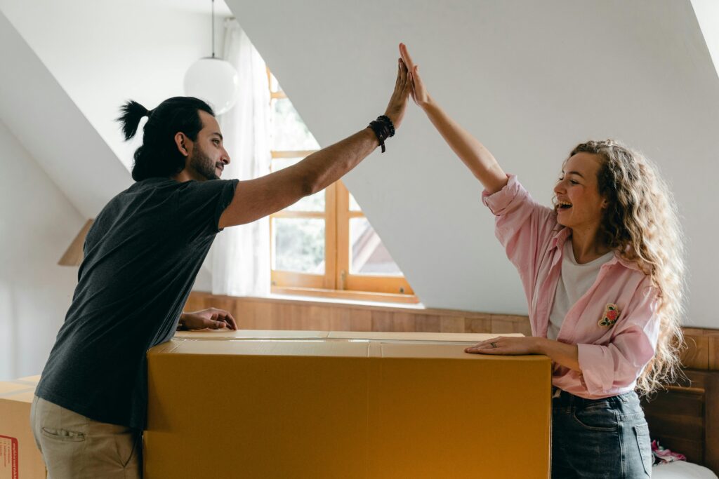 Couple high-fiving each other over a moving box