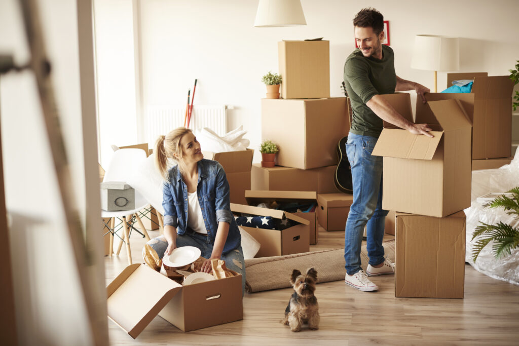 Young couple with moving boxes and a small dog
