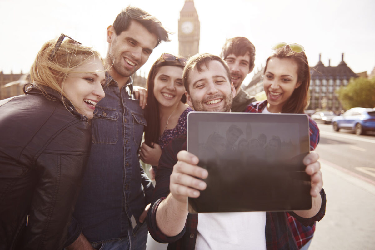 Group of tourists standing taking a selfie on an iPad with Big Ben in the background