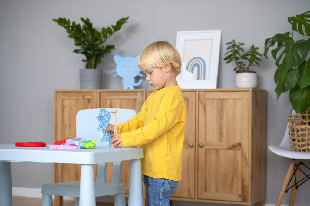 Child in yellow top playing with toys as a table