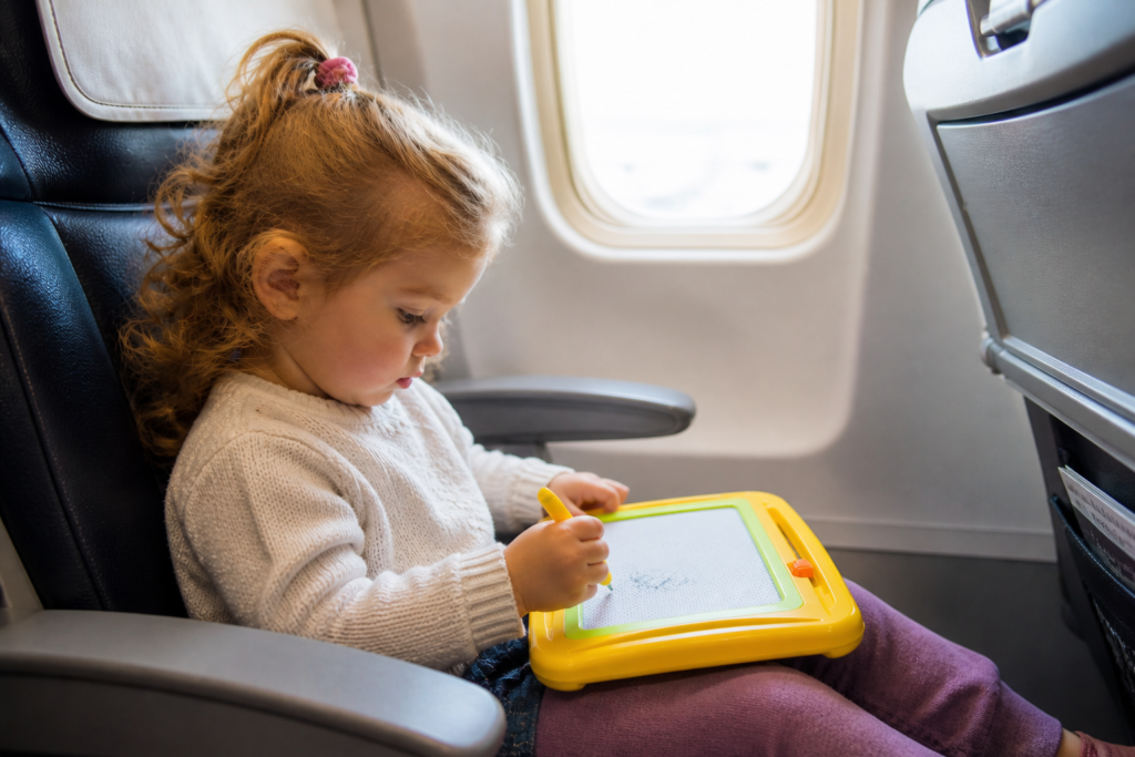 Little girl on an airplane with a doodle toy