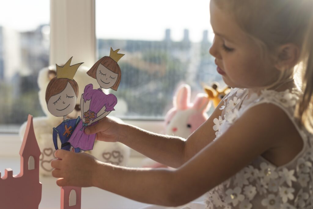 Little girl playing with homemade puppets at home