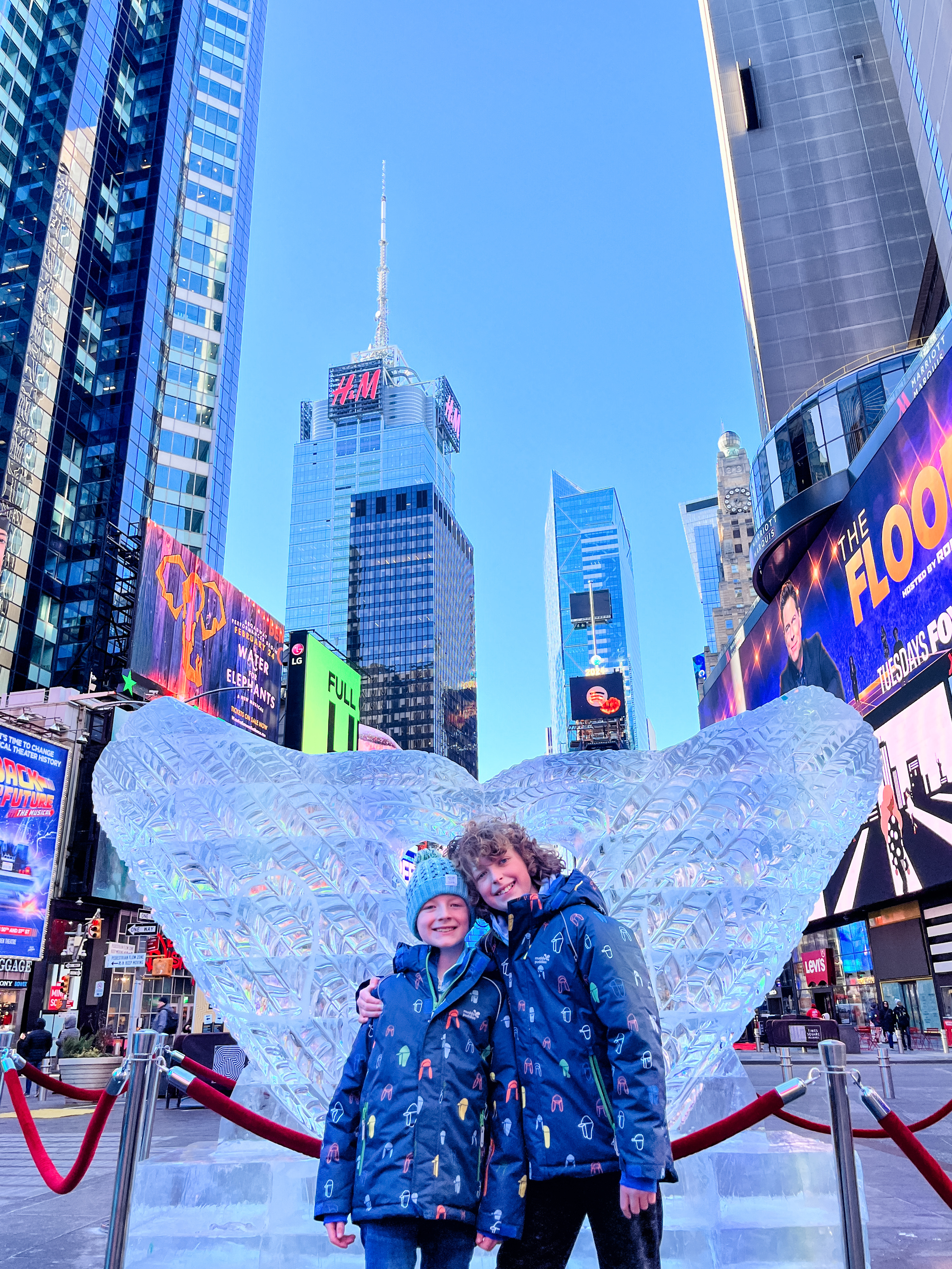 Two boys standing by an ice sculpture in Times Square