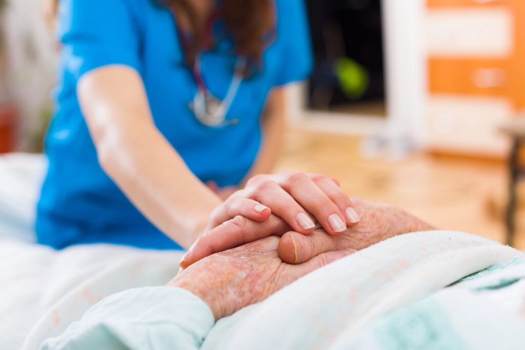 Nursing assistant holding the hand of an elderly patient