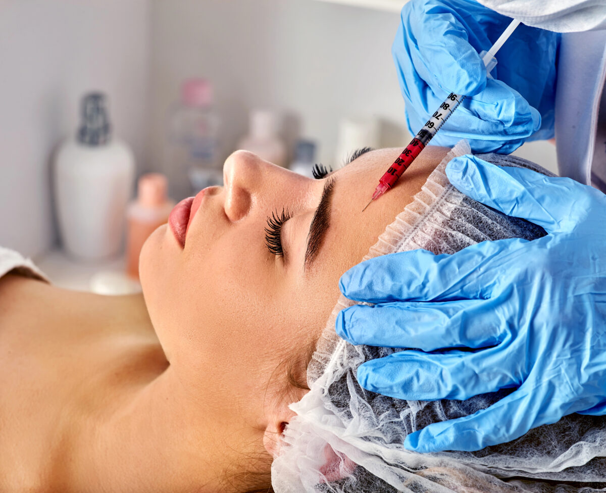 Woman getting facial filler injected into forehead