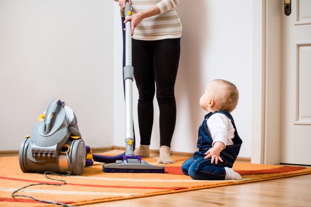 Anon person vacumming with a baby on the floor