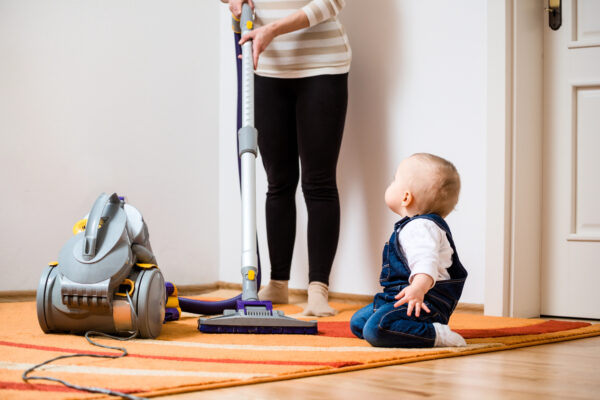 Anon person vacumming with a baby on the floor