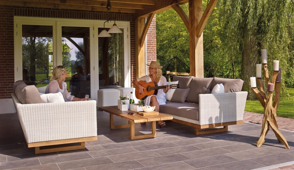 Two women sitting on outdoor sofas on a patio